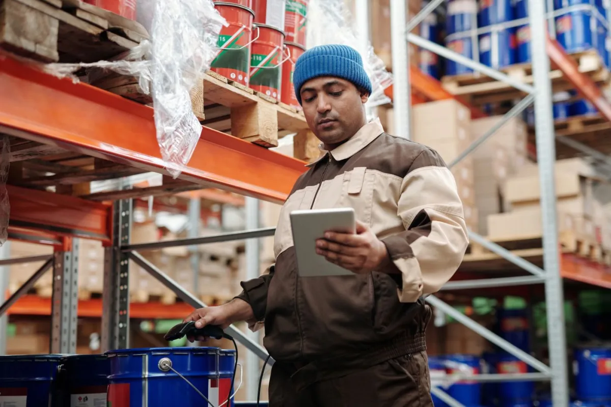 A person checking stock on a shelf against a tablet